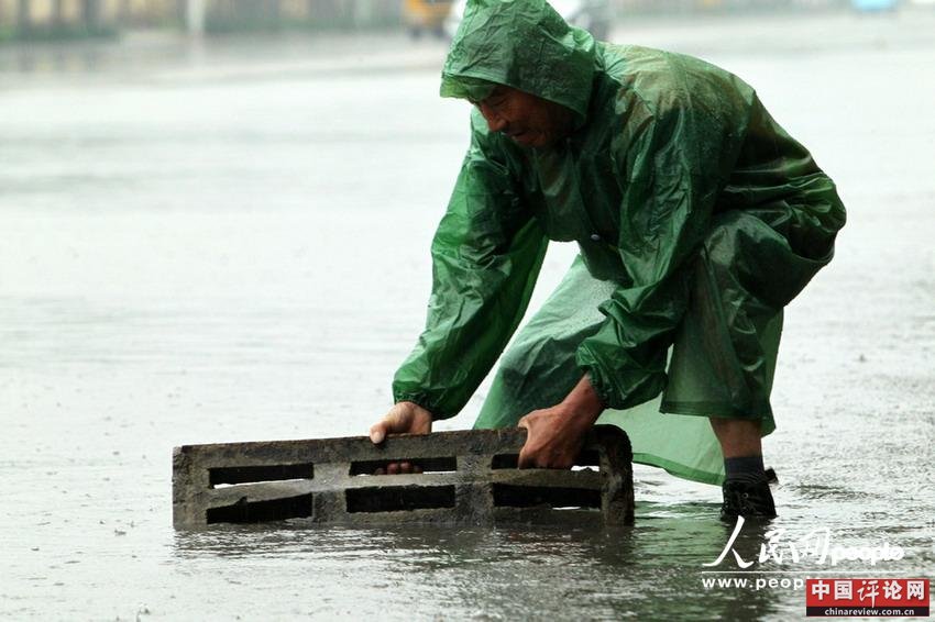　2013年5月26日，一名市政维护人员在河南许昌八一西路积水路段冒雨疏通下水道。牛书培/东方IC 